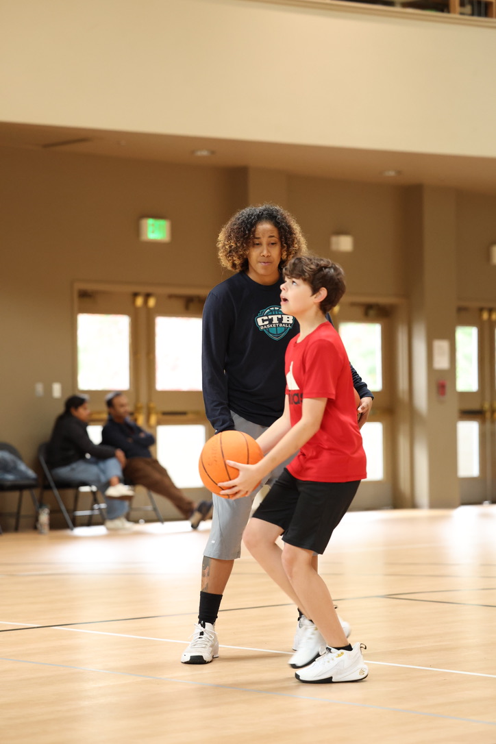 A young female basketball player listening to their coach during a game