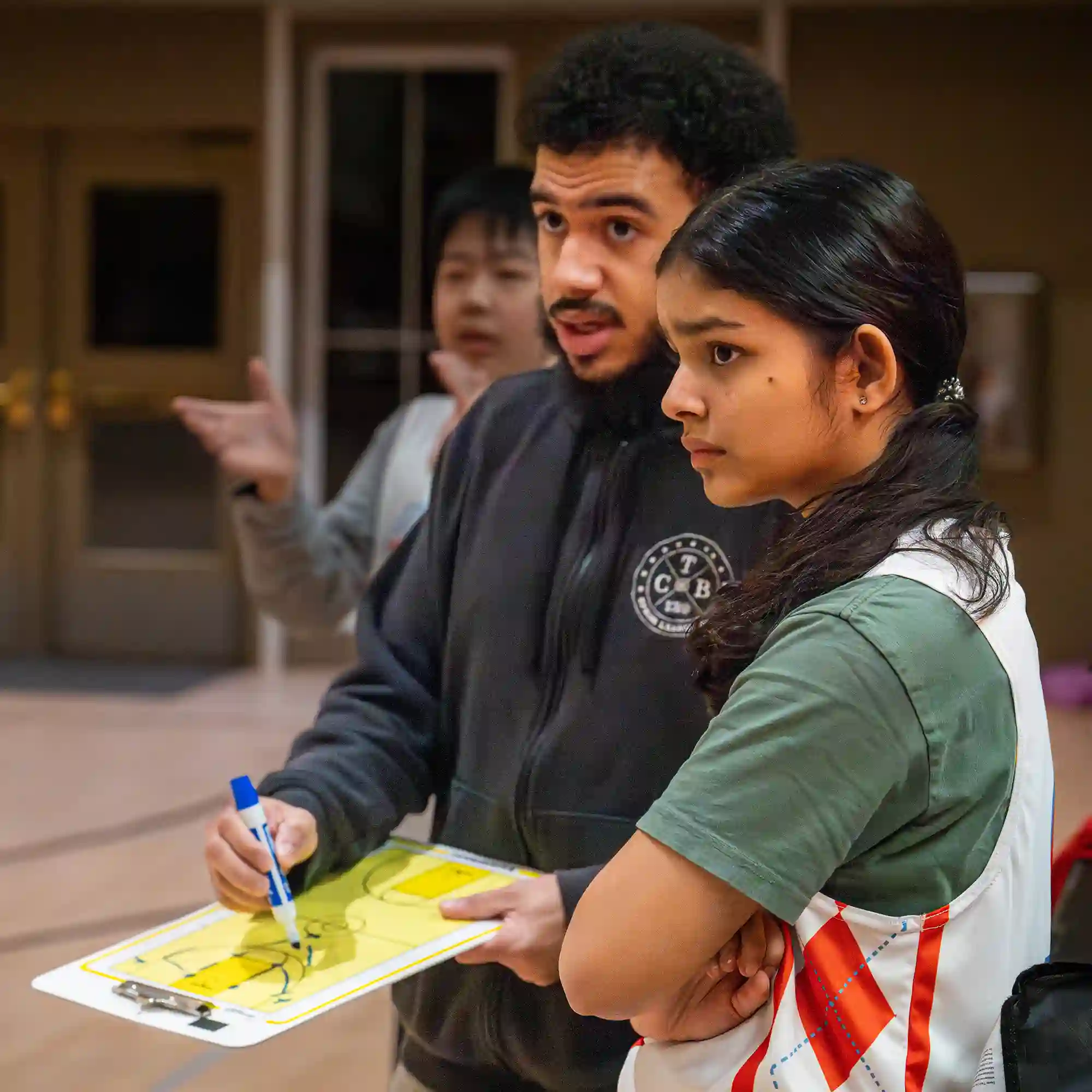 A teenage basketball player going over a play with her coach